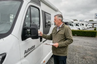 Homme inspectant un camping-car Autostar occasion chez un concessionnaire professionnel