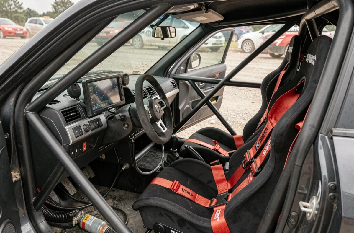 Intérieur préparé d'une voiture de rally avec cage de sécurité, harnais et tableau de bord numérique