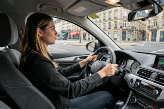 Une jeune femme concentrée au volant d'une voiture d'auto-école dans une rue de Rennes