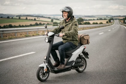Homme à bord d'un scooter électrique Vmaxe sur une route de campagne, prêt pour un long trajet avec bagage fixé