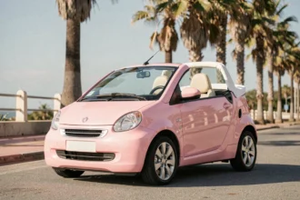 Voiture sans permis décapotable rose garée sur une promenade en bord de mer avec capote abaissée
